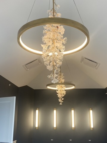 Chandeliers and linear wall lighting installed in a finished vaulted room